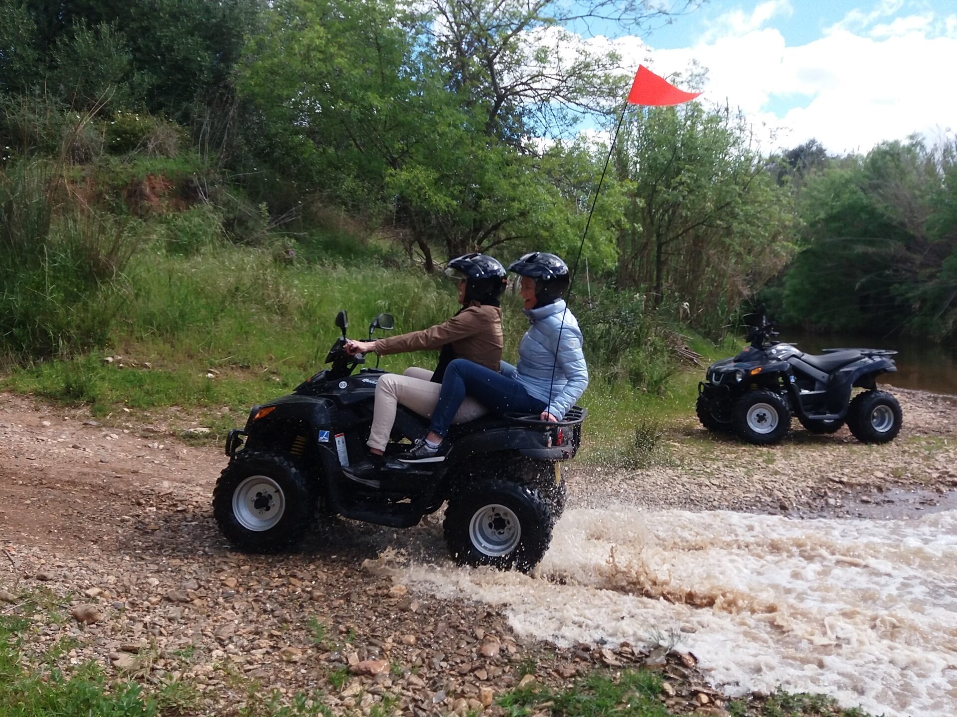 two people riding a quad bike near a river