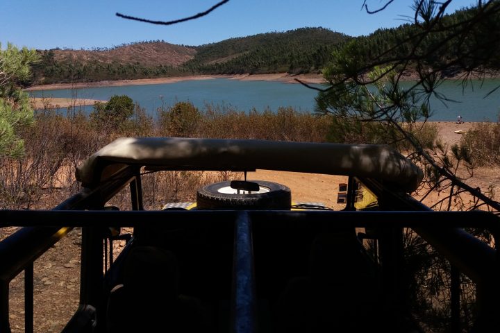 a jeep parked on a field next to a body of water