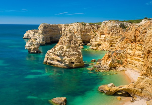 Coastal cliffs with turquoise sea and clear blue sky.