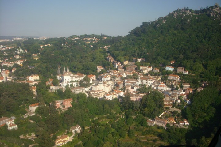 Aerial view of a town nestled among forested hills.