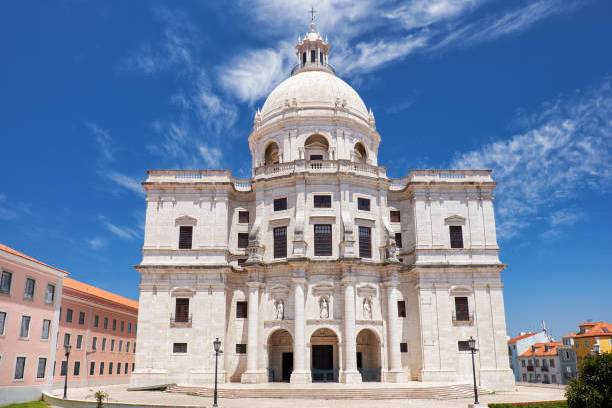 Large white domed building with arches and windows under a blue sky.