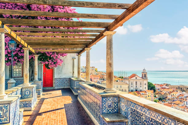 Scenic view from a terrace with tiled railings, flowers, and sea in the background.