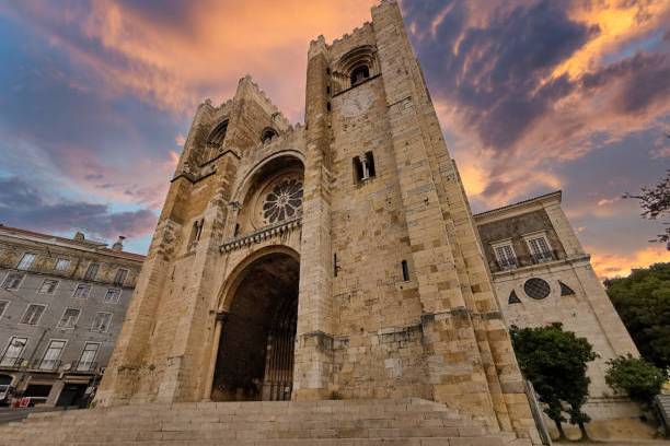 Historic stone cathedral with two towers under a vibrant sunset sky.