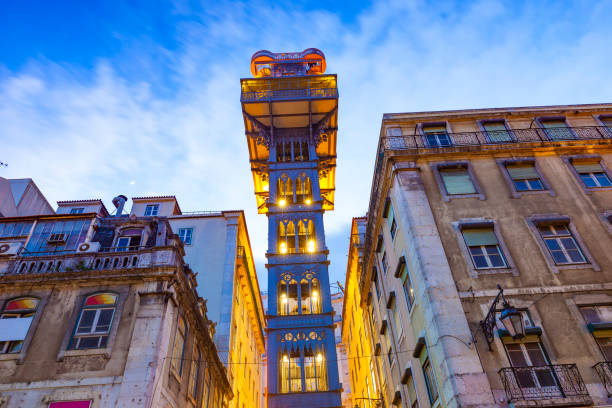 Elevador de Santa Justa illuminated between buildings in Lisbon at dusk.