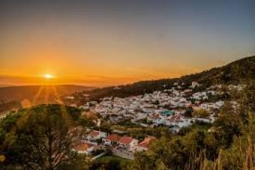 Sunset over a village nestled in green hills.