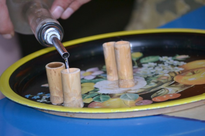 Liquid poured into small bamboo cups on a decorative tray.