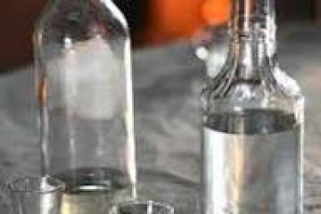 Two bottles and two shot glasses on a reflective surface.